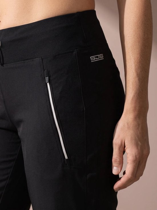 Close-up van het Sjeng Sports logo op een zwarte trainingsbroek met een wit gerande ritssluiting.