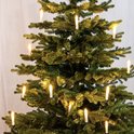 Middelste deel van een groene kunstkerstboom met brandende kaarslampjes.