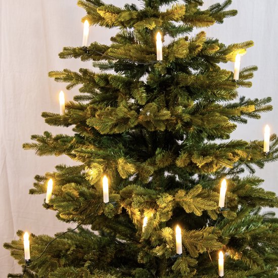 Middelste deel van een groene kunstkerstboom met brandende kaarslampjes.