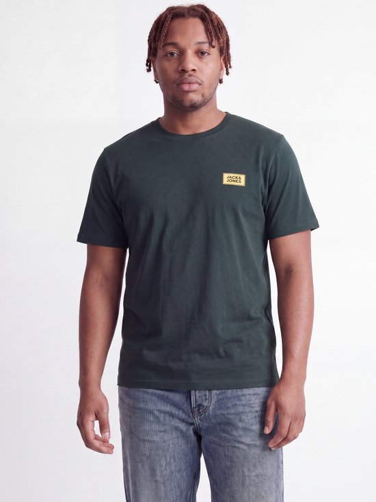 Model draagt een donkergroen T-shirt met ronde hals en een klein geel 'JACK & JONES' logolabel op de borst.