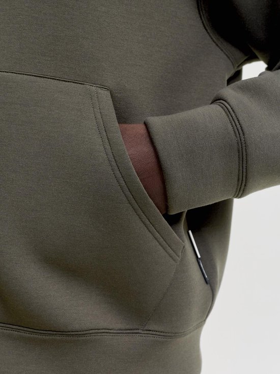 Close-up van de zak van een donkergroene hoodie met een hand erin.