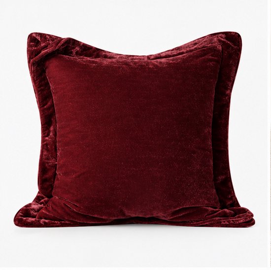 Vierkant bordeauxrood sierkussen van fluweel met een decoratieve geplooide rand op een witte achtergrond.