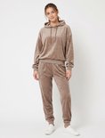 Taupe Apollo velours huispak met capuchon en bijpassende broek, gedragen door een model met witte sneakers.