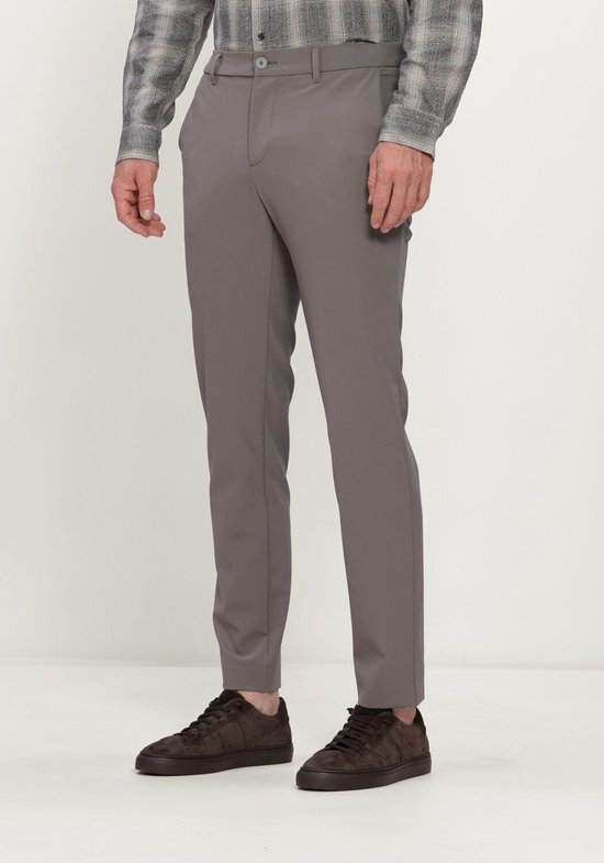 Man in grijze chino broek en grijze geruite blouse, met bruine sneakers.