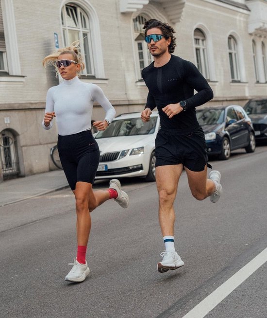 Femme en haut thermique blanc FALKE et homme en haut noir FALKE courant dans la rue avec des lunettes de soleil.