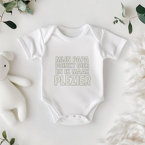 Wit babyrompertje met de tekst: MIJN PAPA DRINKT BIER EN IK MAAK PLEZIER, naast een knuffelkonijn.