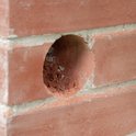 Een rond gat in een rode bakstenen muur, voorbereid voor een boor.