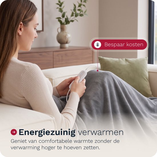 Vrouw op een bank met een grijze elektrische deken omgeslagen en een afstandsbediening.