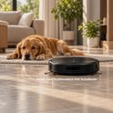 Zwarte robotstofzuiger ideaal voor huishoudens met huisdieren, naast een hond op een tapijt.