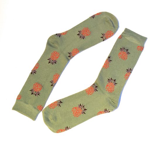 Lichtgroene sokken met een patroon van oranje ananassen met paarse bladeren.