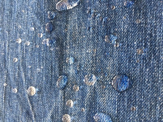 Waterdruppels op blauw denim met textuur.