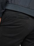 Close-up van de achterzak van een zwarte chino met donkerblauw bomberjack.