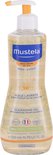 Fles Mustela doucheolie met gele pompdispenser. De fles heeft een golvend ontwerp en groene bladerprint.