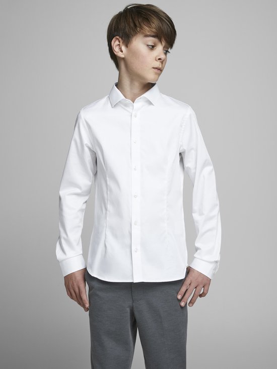 Garçon portant une chemise blanche à manches longues avec des boutons blancs et un pantalon gris.