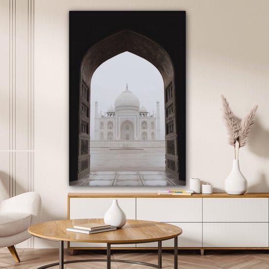 Une peinture du Taj Mahal à travers une arche, accrochée au-dessus d'un buffet dans un salon.