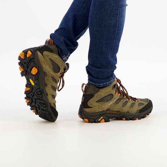 Zijaanzicht van Merrell Moab 3 wandelschoenen met olijfgroen suède, zwarte zool en oranje Vibram-details.