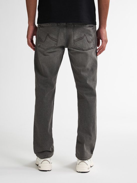Achterkant van een man in een zwarte T-shirt en grijze jeans.