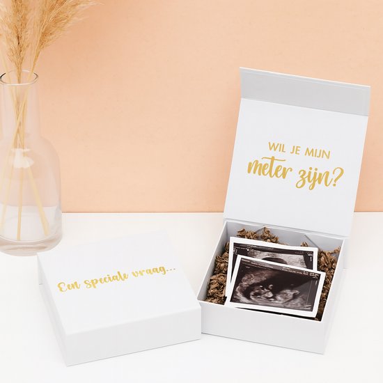 Une boîte cadeau blanche ouverte avec le texte doré 'Veux-tu être ma marraine ?' et des échographies sur une garniture marron. La boîte fermée porte le texte 'Une question spéciale...'.