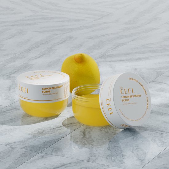 Twee potjes en een citroen op een marmeren achtergrond. De potjes bevatten een gele bodyscrub.