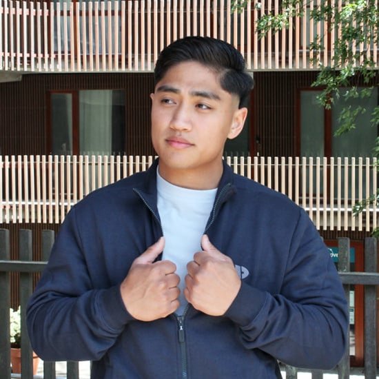 Man draagt een donkerblauwe sweater met ritssluiting en een lichtgrijs T-shirt eronder.
