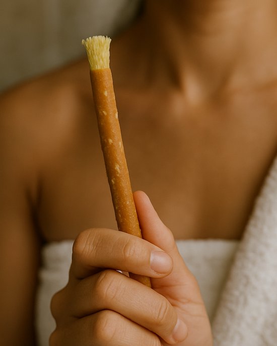 Hand houdt een Miswak takje vast met zachte vezels aan het uiteinde.
