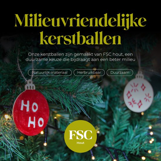 Twee houten kerstballen aan een kerstboom, één rood met 'HO HO HO' en één wit met rode patronen.