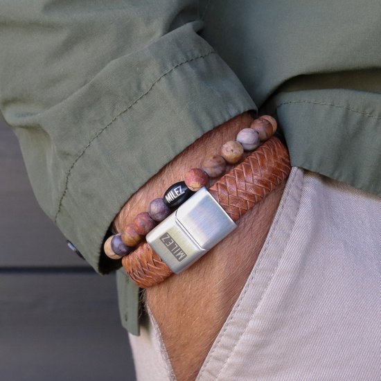 Leren armband met gevlochten band en stenen kralen, gedragen door een man met een groen jack en beige broek.