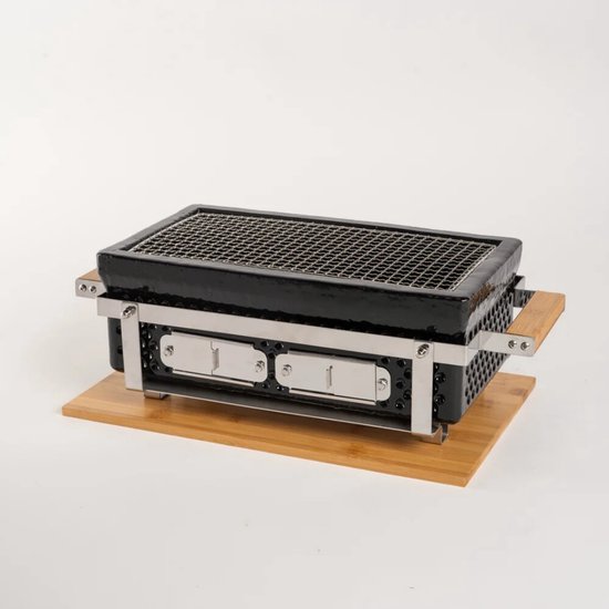 Zwarte, rechthoekige hibachi BBQ met houten handvatten, op een houten onderzetter, tegen een witte achtergrond.
