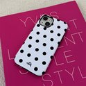 Witte telefoonhoes met zwarte stippen op een roze boek met tekst.