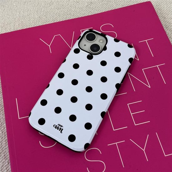 Witte telefoonhoes met zwarte stippen op een roze boek met tekst.