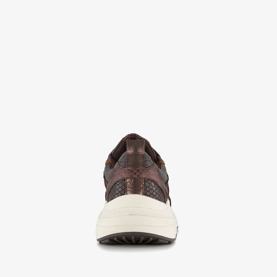 Achterkant van bruine sneaker met slangenprint en beige zool.