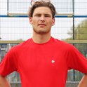 Man draagt een rood sportshirt met korte mouwen, met de handen in de zij.
