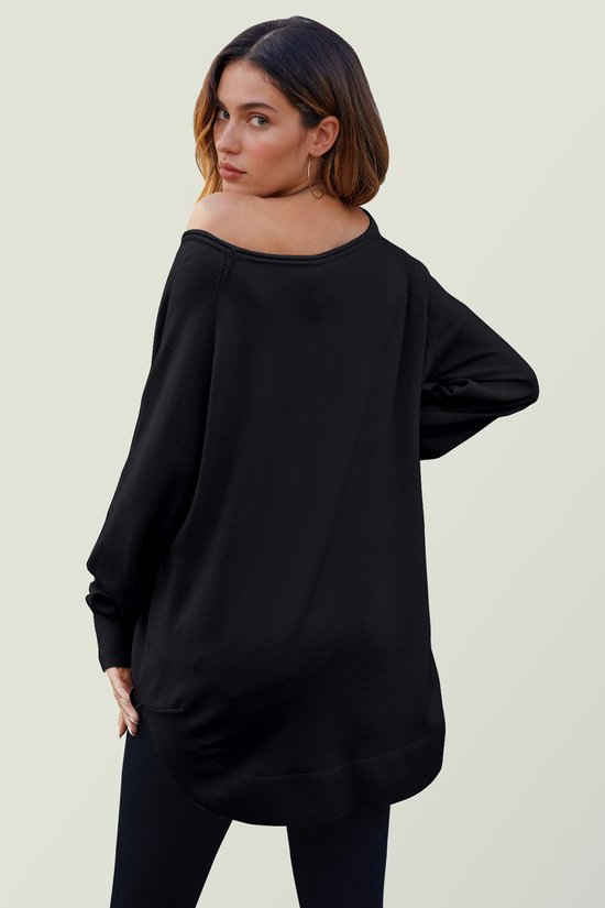 Zijaanzicht van model die een oversized zwarte gebreide trui draagt, de trui heeft een wijde halslijn die over één schouder valt.