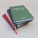 Stapel dagboeken in groen, blauw, beige en rood, met linten in verschillende kleuren.