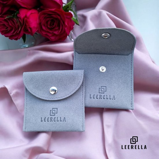 Twee grijze suède juwelendoosjes met het Leerella logo, naast roze satijn en rode rozen.