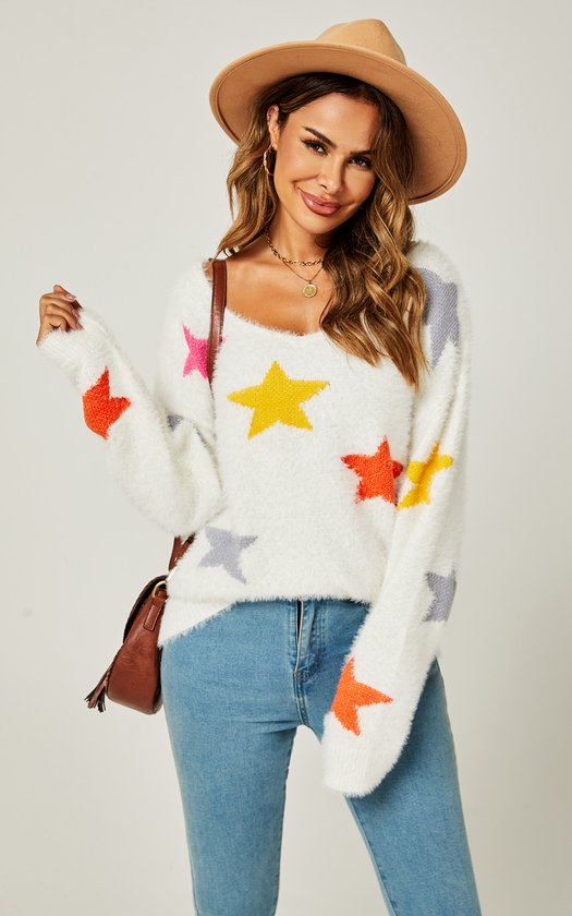Model draagt witte, pluizige trui met veelkleurige sterrenprint. Blauwe jeans, bruine hoed en bruine tas.