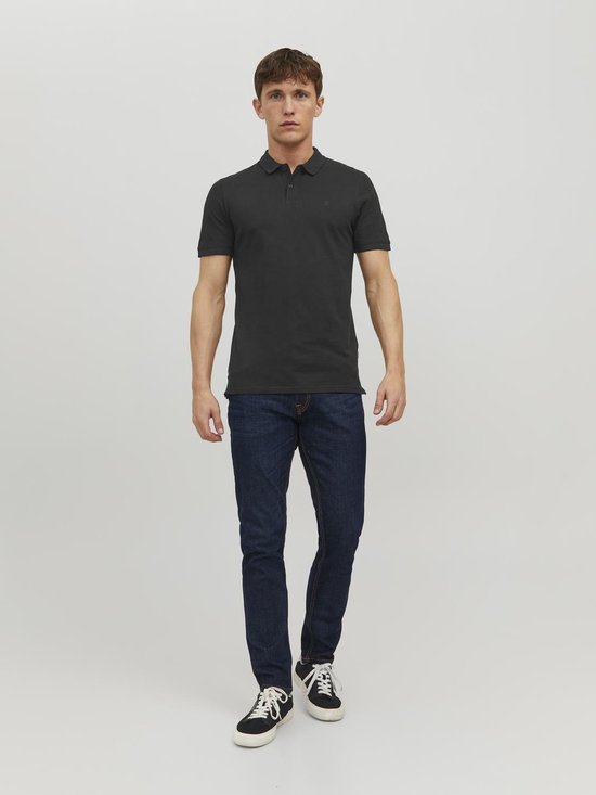 Man met donkergrijs pique polo shirt met korte mouwen en spijkerbroek.