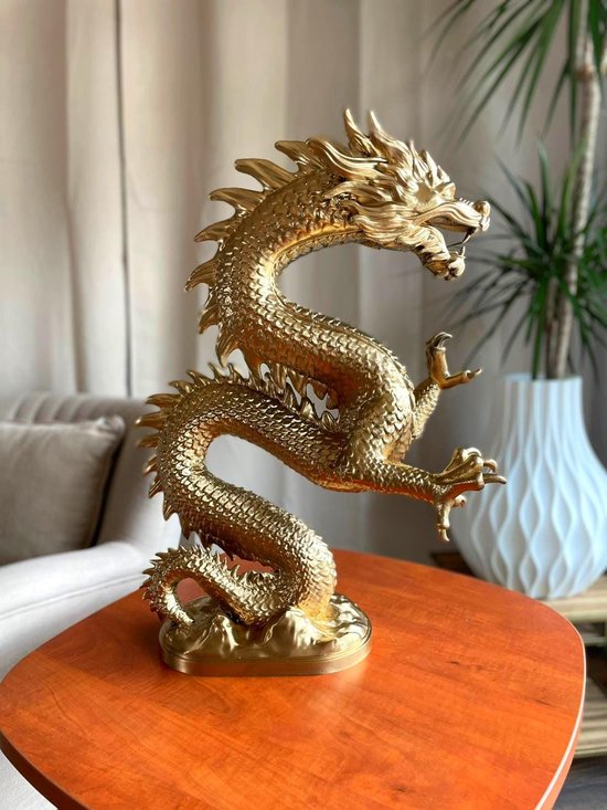 Gouden drakenbeeld met schubben en klauwen op een tafel.