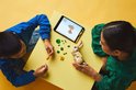 Enfants construisant des animaux LEGO avec tablette, vu de dessus.