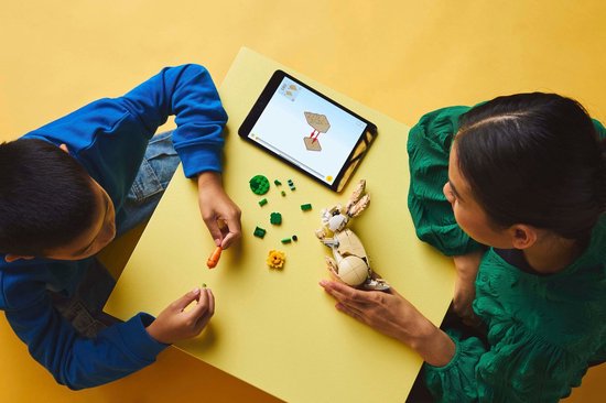 Enfants construisant des animaux LEGO avec tablette, vu de dessus.