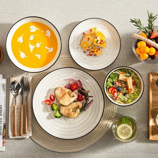 Beige servies met zwarte rand, gedekt met soep, salade, vlees en dessert. De gespikkeld textuur is zichtbaar.