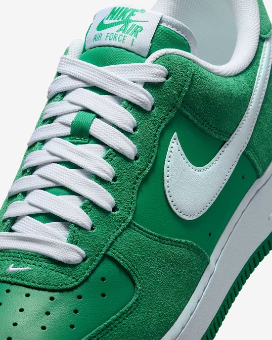Detail van de veters en witte Swoosh op een groene Nike Air Force 1 '07 LV8 sneaker.