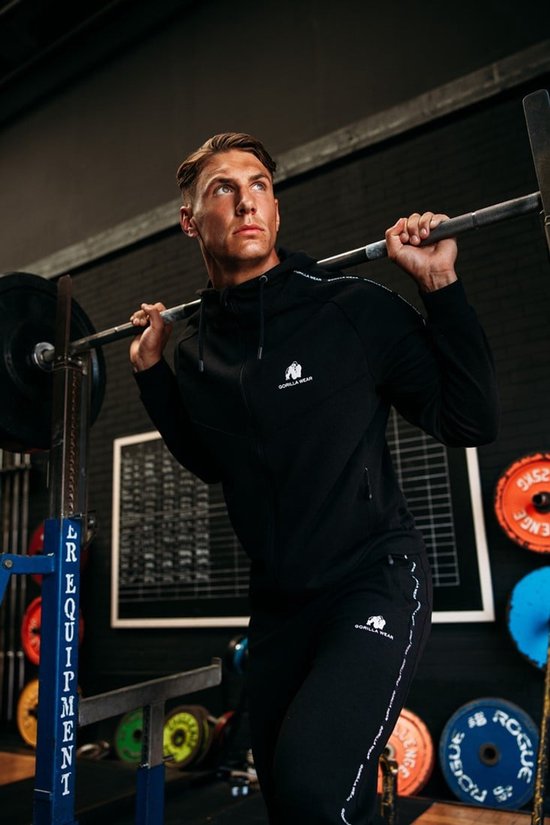 Man met spierbundel met trainingsjas en trainingsbroek van Gorilla Wear in de sportschool.