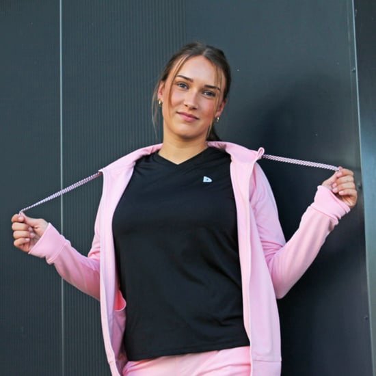 Jongedame met open lichtroze vest over een zwart shirt, houdt de koordjes vast.