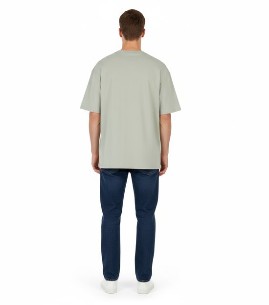 Man met donkerblauwe jeans en lichtgroen oversized T-shirt met korte mouwen, van achteren gezien.