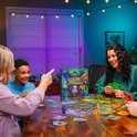 Familie speelt Disney Villainous Unstoppable aan tafel met spelbord en kaarten.
