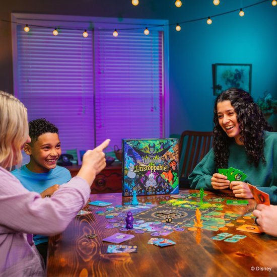 Familie speelt Disney Villainous Unstoppable aan tafel met spelbord en kaarten.