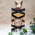 Oud Mood parfumfles met gouden dop, omwikkeld met zwart lint met "Oud Mood" erop. Op een witte ondergrond met groene bladeren.