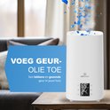 Witte Aironex luchtbevochtiger met stoom, digitale display en blauwe blaadjes die eruit vallen. Het 'Voeg geur-olie toe' gedeelte wordt benadrukt.