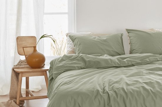 Lichtgroen katoenen dekbed met twee kussenslopen op een bed, met een houten stoel ernaast.
